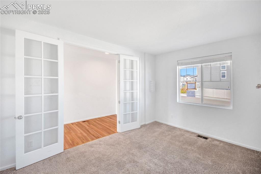 Image 13 of 46: Carpeted empty room with french doors and baseboards