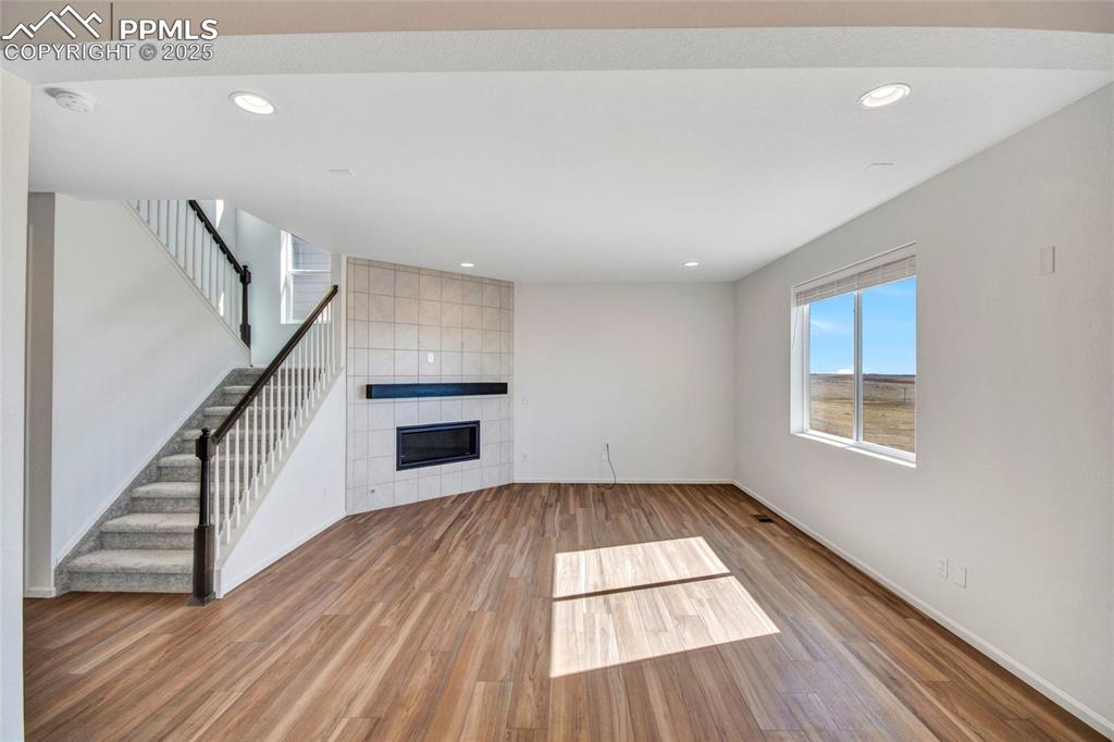 Image 15 of 46: Unfurnished living room with a tile fireplace, wood finished floors, recess