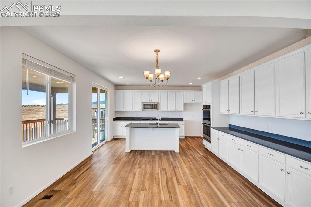 Image 16 of 46: Kitchen featuring dark countertops, white cabinets, pendant lighting, light