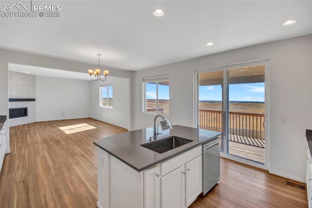 Image 19 of 46: Kitchen featuring white cabinets, light wood finished floors, open floor pl