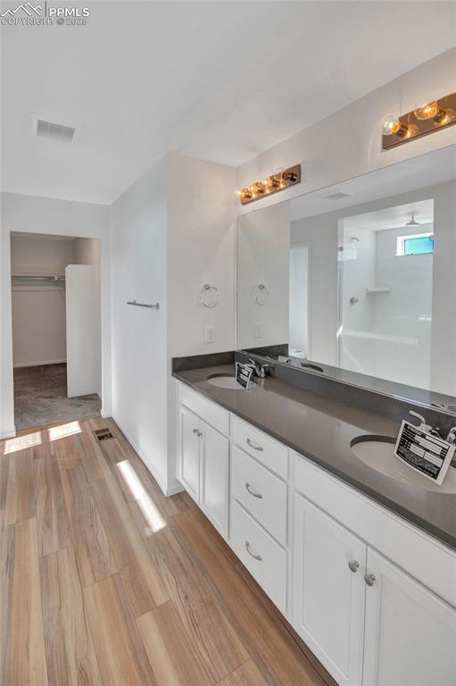 Image 34 of 46: Full bath with walk in shower, double vanity, light wood finished floors, a