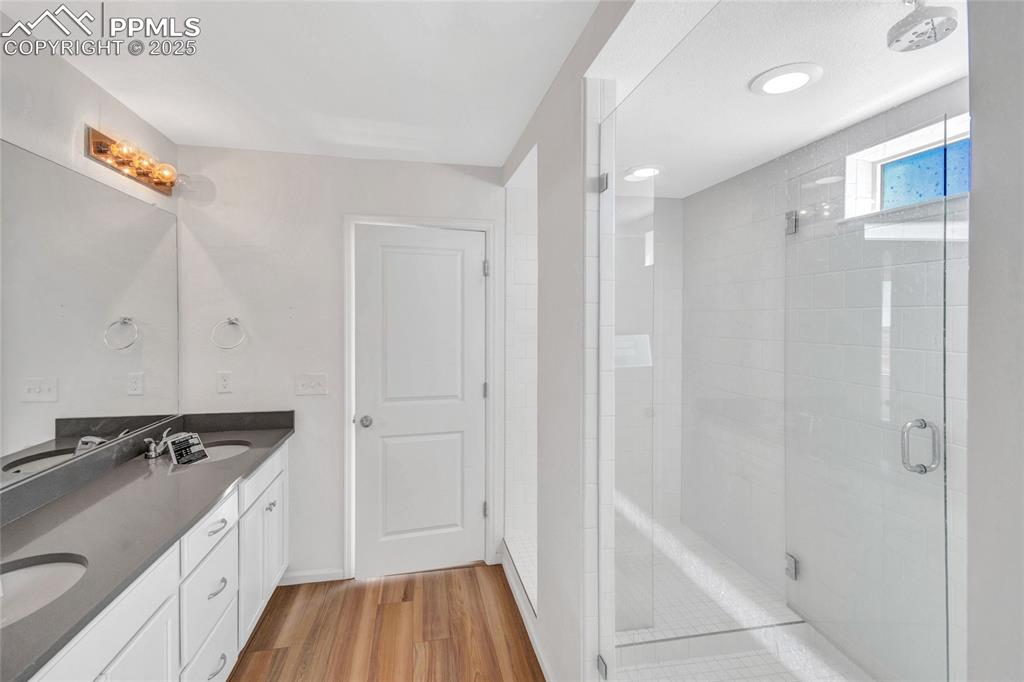 Image 36 of 46: Bathroom featuring double vanity, a stall shower, and light wood-type floor