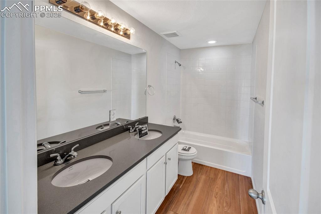 Image 37 of 46: Full bathroom featuring double vanity, light wood-style flooring, shower /