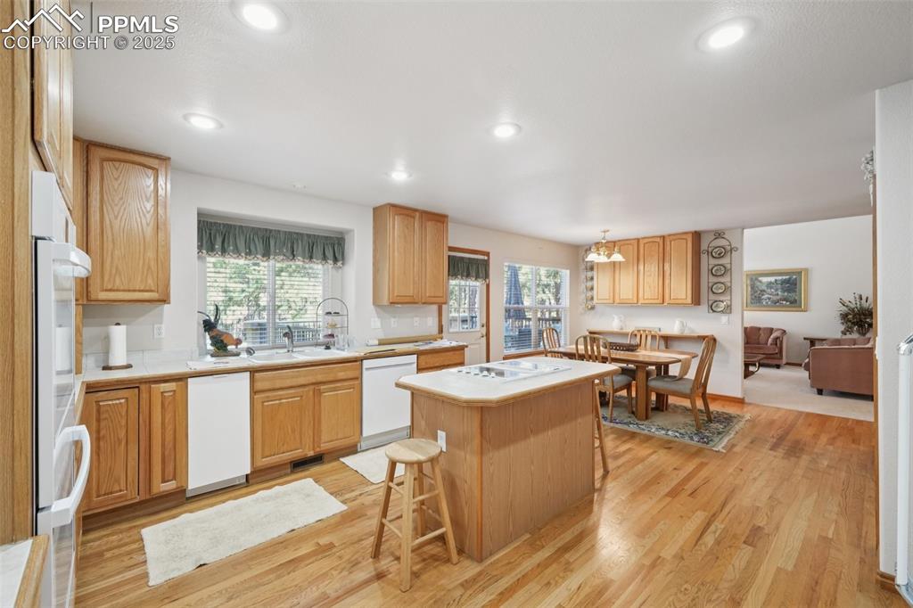 Image 17 of 45: Kitchen featuring a kitchen bar, light wood finished floors, white applianc