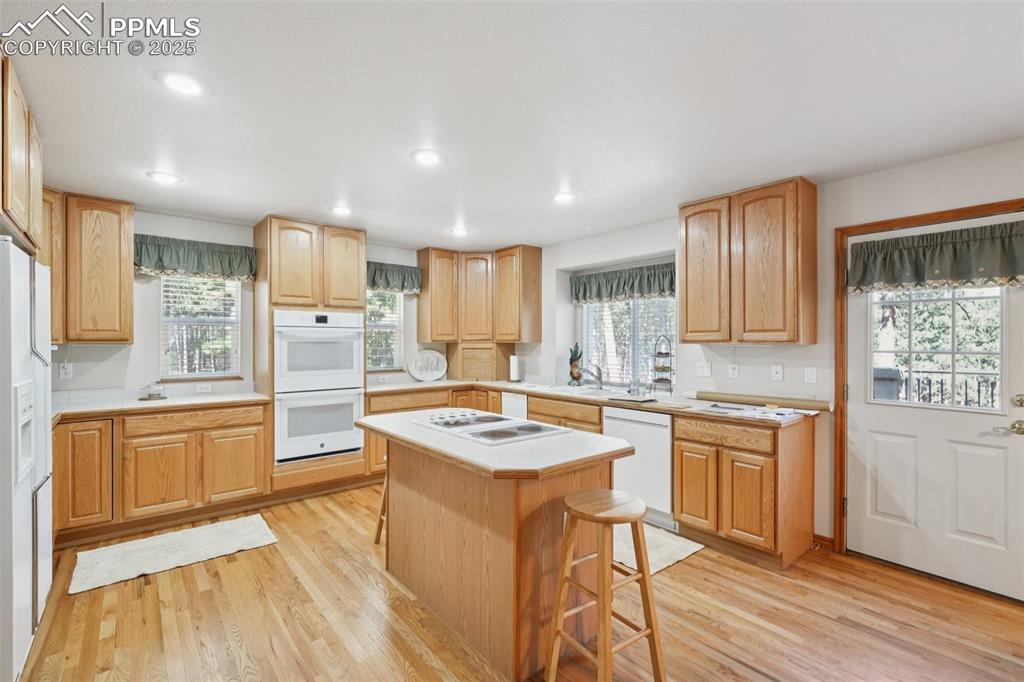 Image 18 of 45: Kitchen featuring light wood-type flooring, a kitchen bar, healthy amount o
