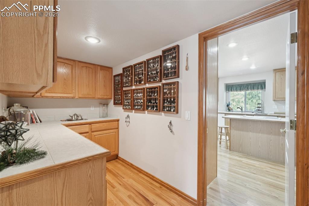 Image 20 of 45: Bar area featuring light wood finished floors, light brown cabinets, recess