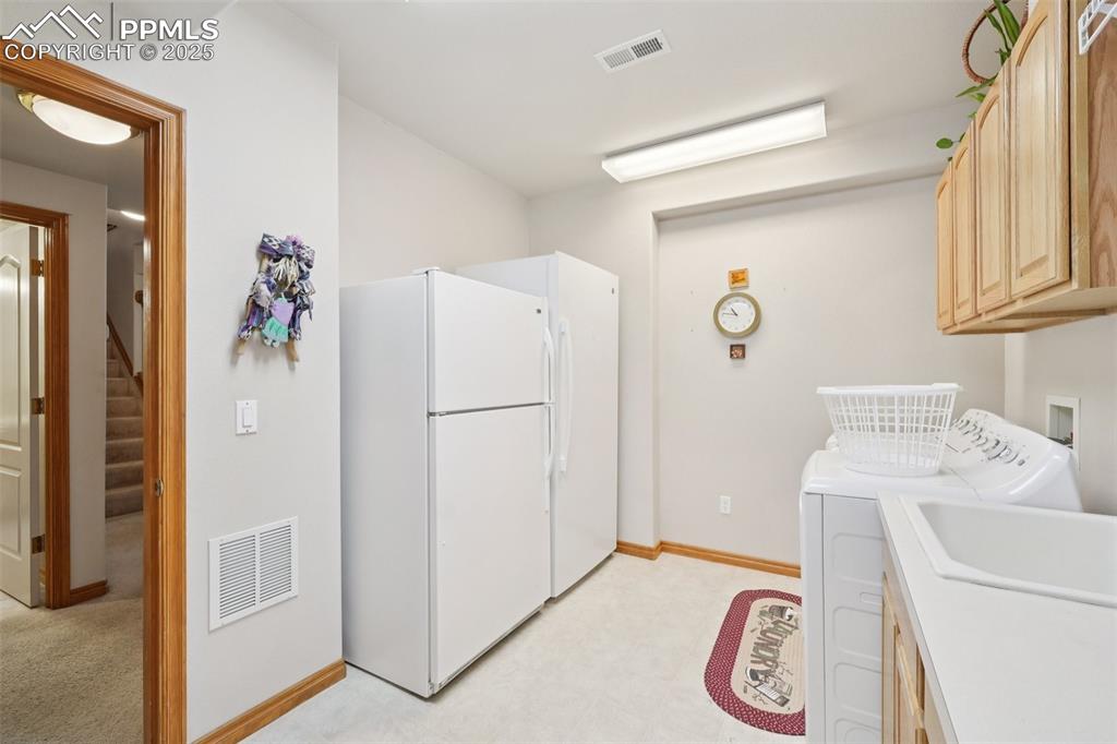 Image 31 of 45: Laundry room featuring light flooring, washer and dryer, and cabinet space