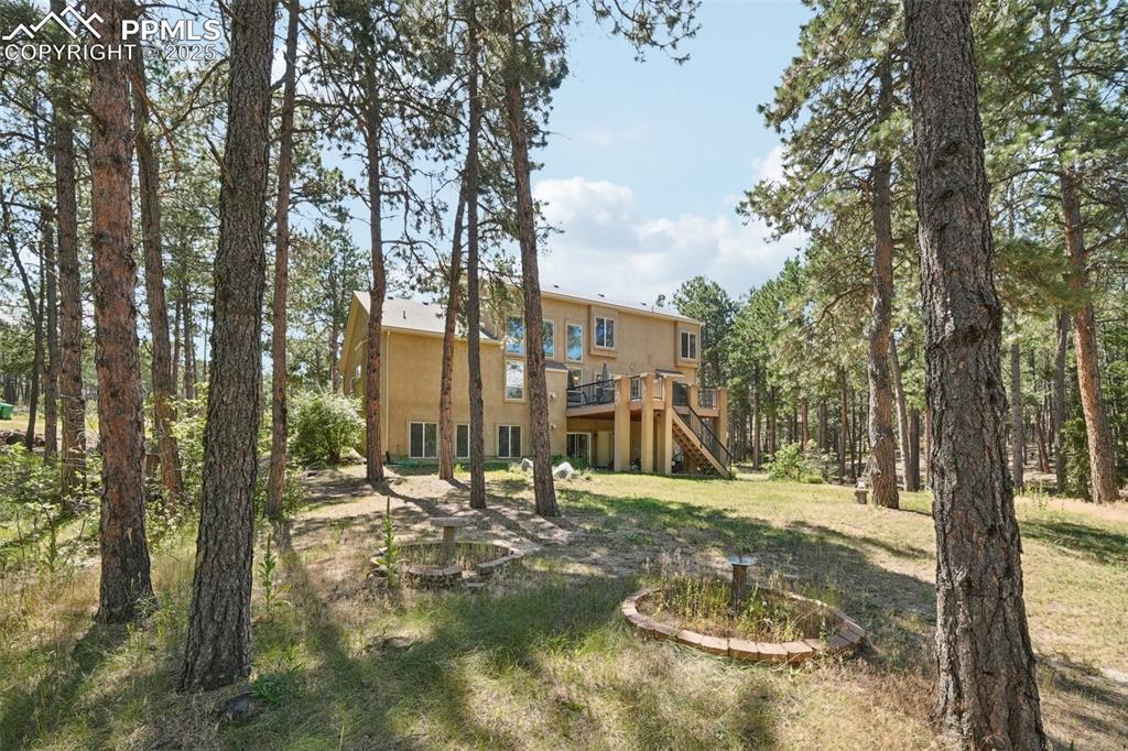Image 39 of 45: Rear view of house with stairs, a deck, a lawn, and stucco siding