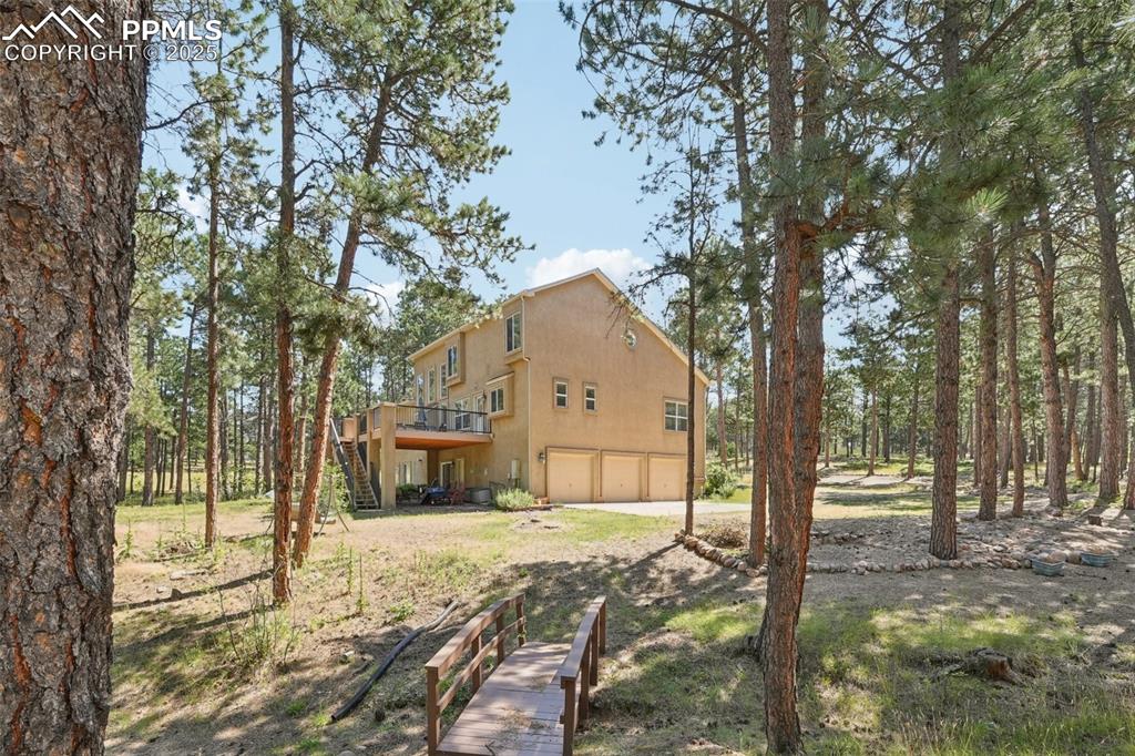 Image 40 of 45: Rear view of house featuring stairs, an attached garage, a wooden deck, and