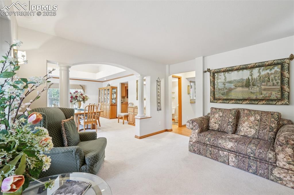 Image 5 of 45: Living area featuring carpet flooring, ornate columns, a tray ceiling, and