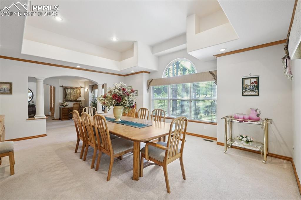 Image 9 of 45: Carpeted dining room with arched walkways, ornate columns, recessed lightin
