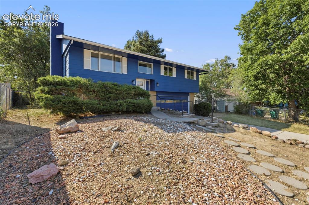 Image 1 of 46: Split-level residence featuring a vibrant blue exterior and white trim