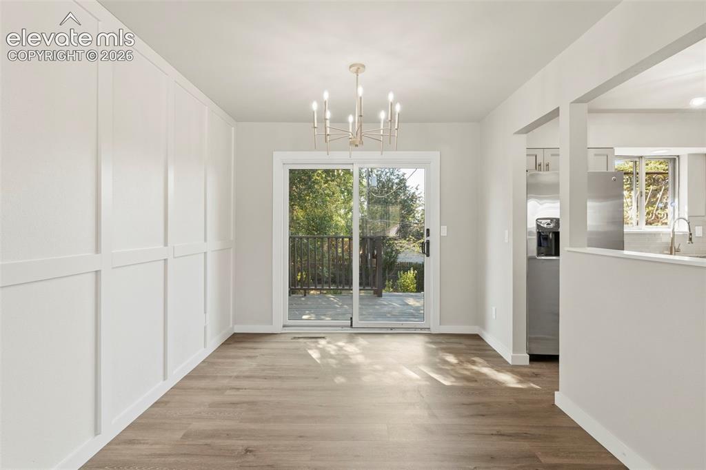 Image 12 of 46: Dining area with luxury vinyl plank flooring, a contemporary chandelier, an