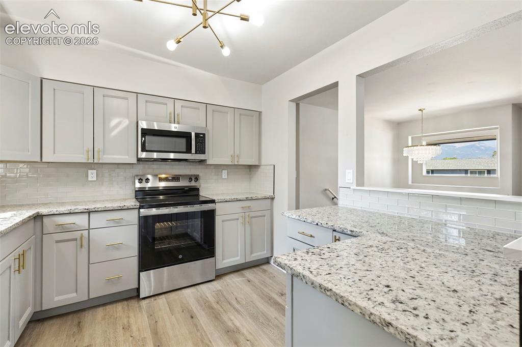 Image 14 of 46: Kitchen featuring gray cabinetry, stainless steel appliances, granite count