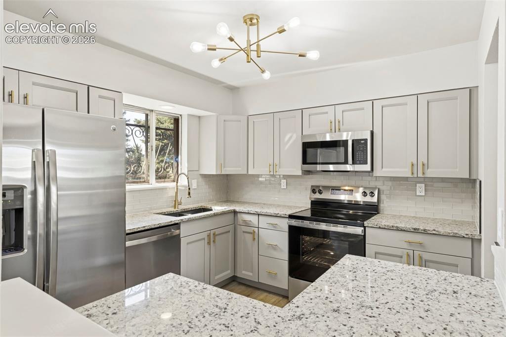 Image 15 of 46: Kitchen featuring gray cabinetry, stainless steel appliances, granite count