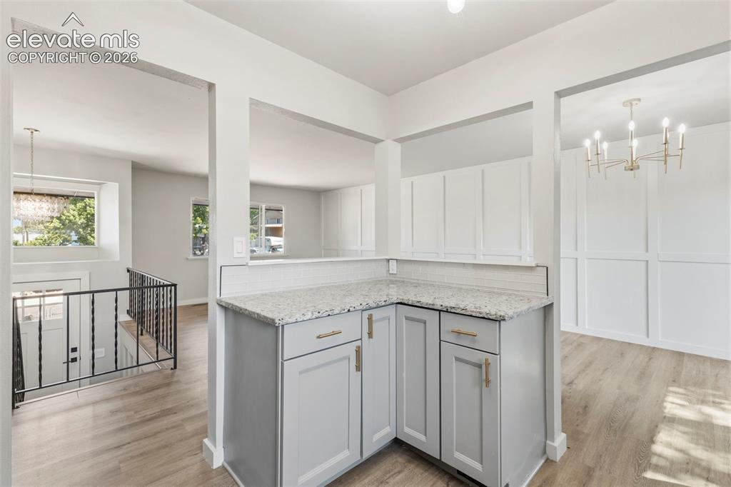 Image 19 of 46: Corner peninsula featuring gray cabinetry with gold hardware, granite count