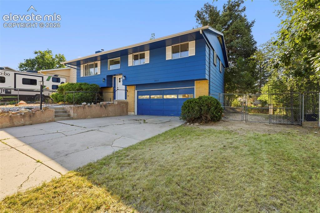 Image 2 of 46: Bi-level residence featuring a blue exterior and an attached garage with a