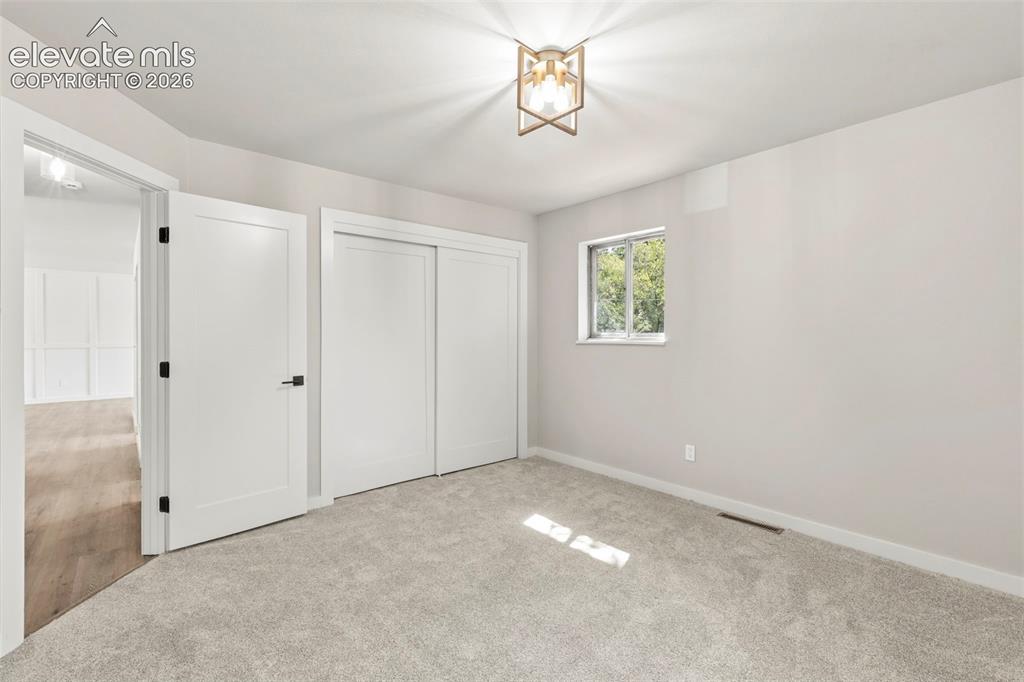 Image 23 of 46: Carpeted room featuring white trim, and a gold-finish semi-flush mount ligh