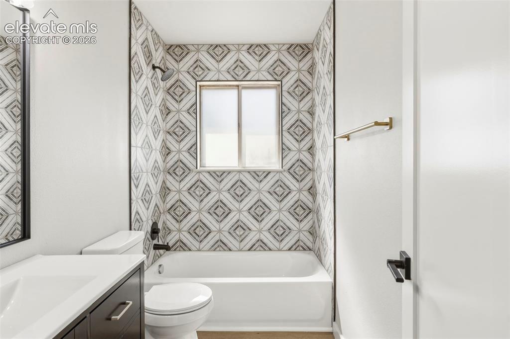 Image 25 of 46: Bathroom featuring a white bathtub with a tile surround and a vanity with a