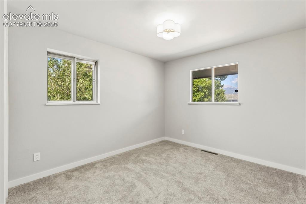 Image 26 of 46: Light taupe carpeted room featuring two windows, a white baseboard, light g