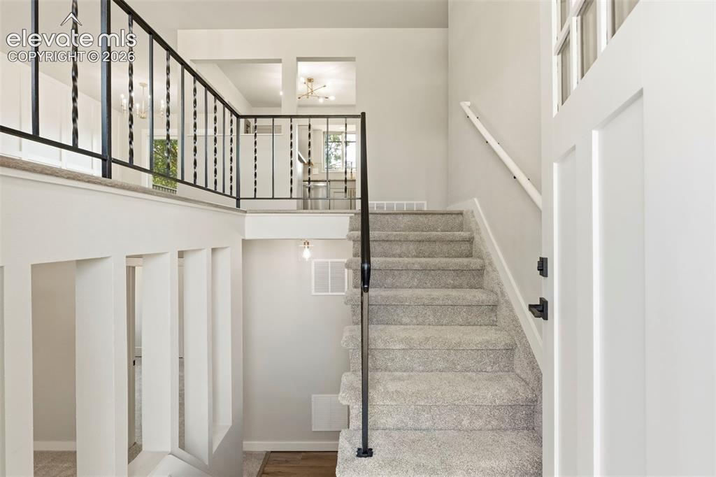 Image 3 of 46: Open entryway featuring a light-colored carpeted staircase with a black wro
