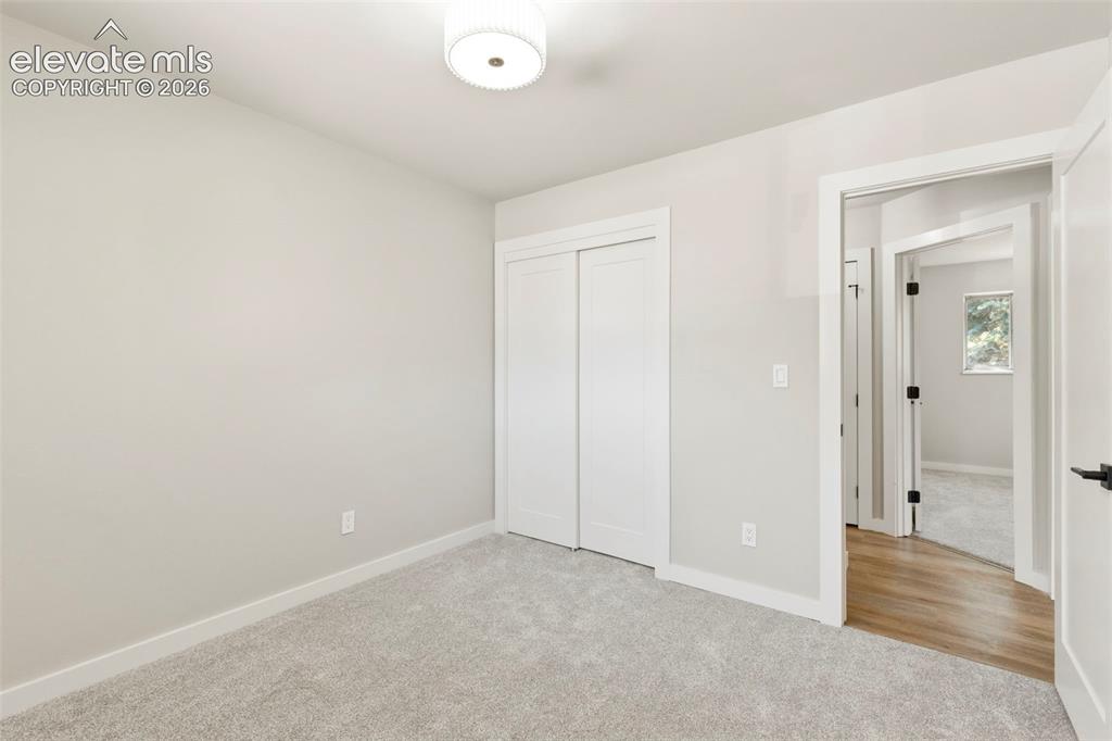 Image 31 of 46: Neutral-toned room featuring light taupe carpet, white baseboards, and a wh