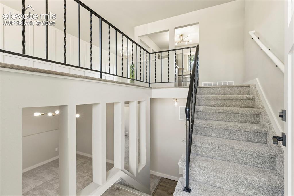 Image 4 of 46: Split-level entry featuring carpeted stairs with a black wrought iron raili
