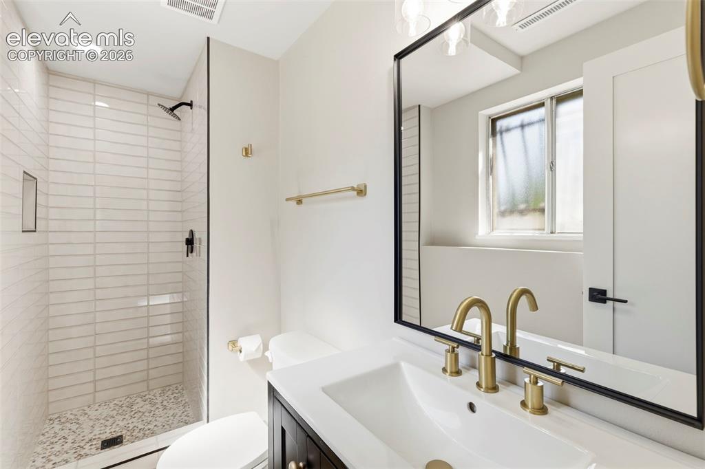 Image 43 of 46: Bathroom featuring a frameless glass shower enclosure with horizontal tile,