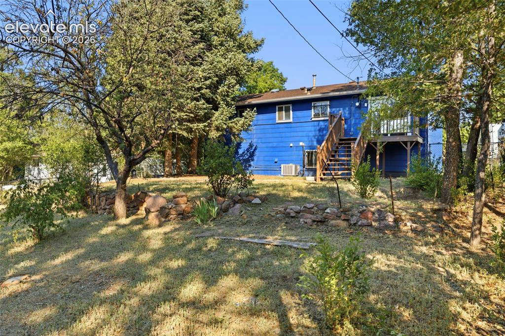 Image 46 of 46: Split-level residence featuring a vibrant blue exterior, a rear wood deck,