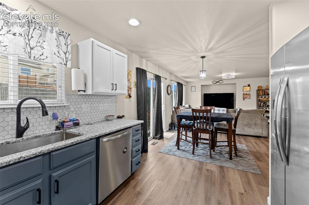 Image 10 of 41: Open-concept kitchen and dining area featuring a hexagonal tile backsplash,