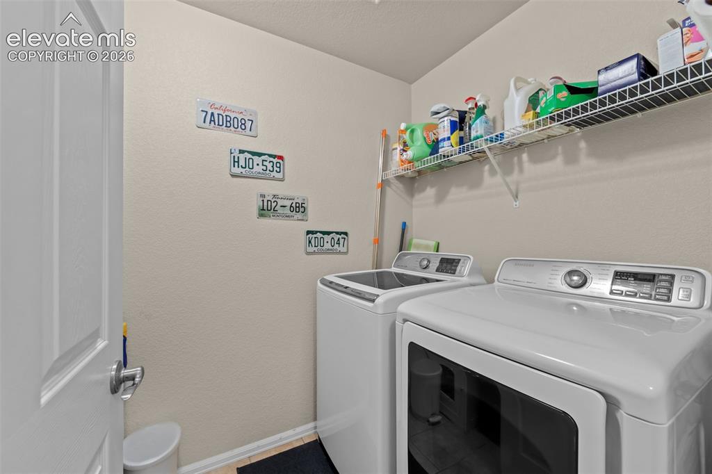 Image 18 of 41: Utility area featuring a top-load washing machine, front-load dryer, and in