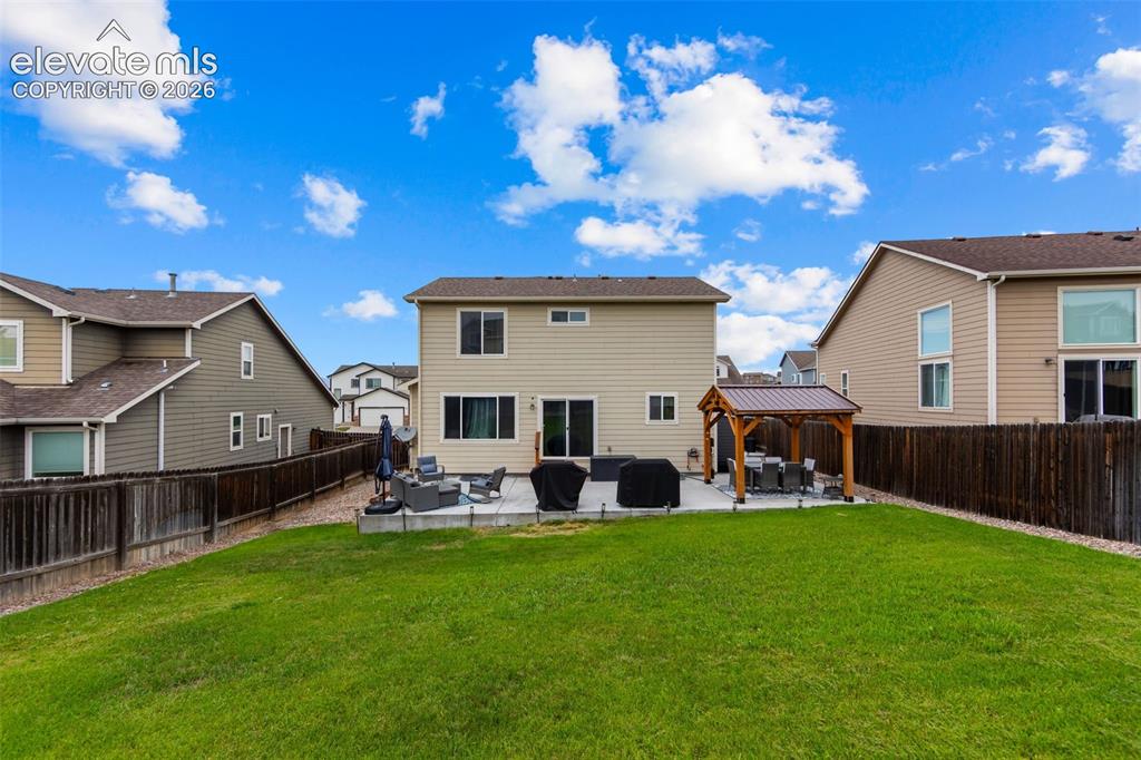 Image 28 of 41: Expansive backyard featuring a large concrete patio, a built-in pergola, an