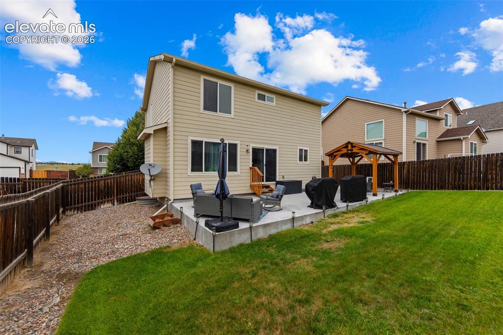 Image 30 of 41: Expansive backyard featuring a manicured lawn, concrete patio, and a wood g