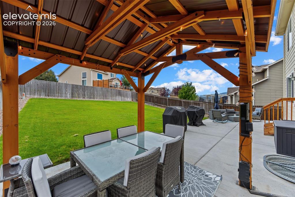 Image 31 of 41: Expansive backyard featuring a covered patio with wood beam construction, a