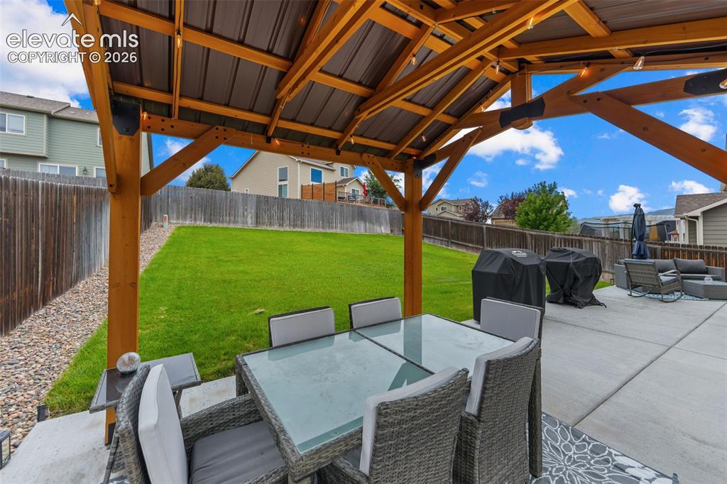 Image 32 of 41: Patio featuring a wood pergola with a metal roof, concrete hardscaping, and