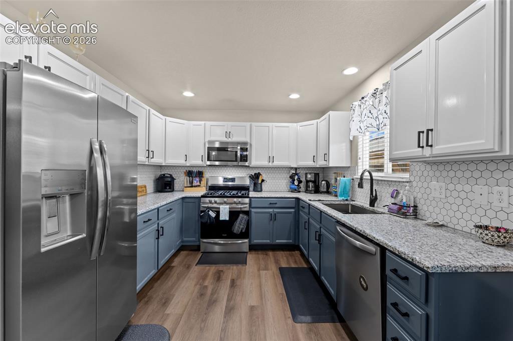 Image 8 of 41: Stainless steel appliances, wood-finish flooring, two-tone cabinetry, hexag
