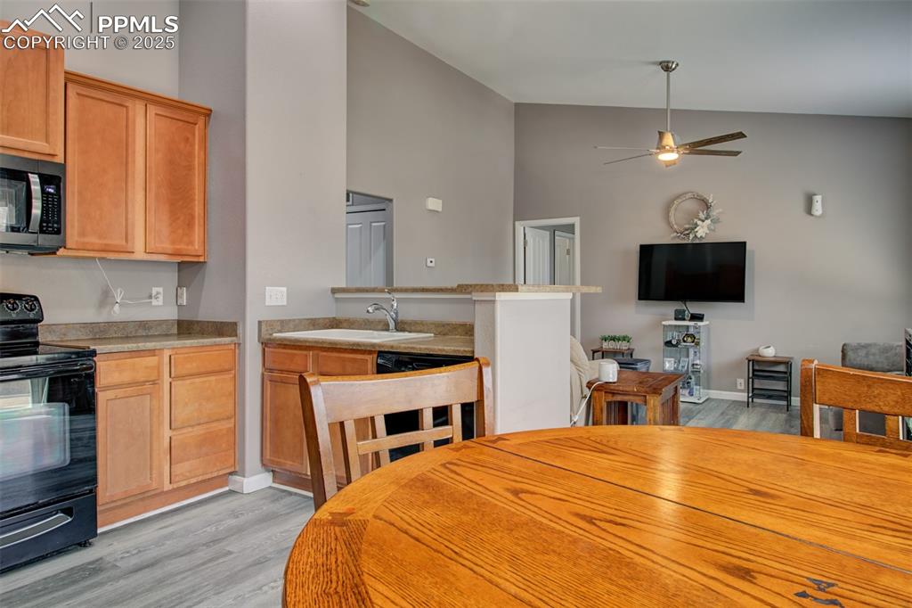 Image 10 of 21: Kitchen featuring black electric range, a ceiling fan, light wood-type floo