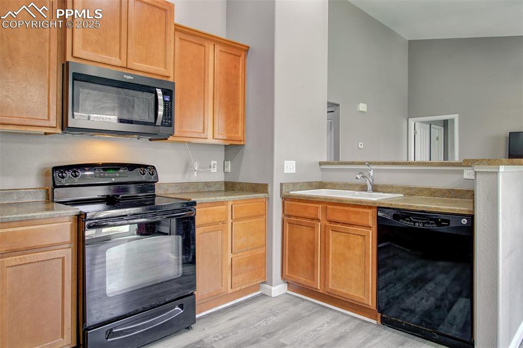 Image 12 of 21: Kitchen featuring black appliances, light wood-style flooring, a peninsula,