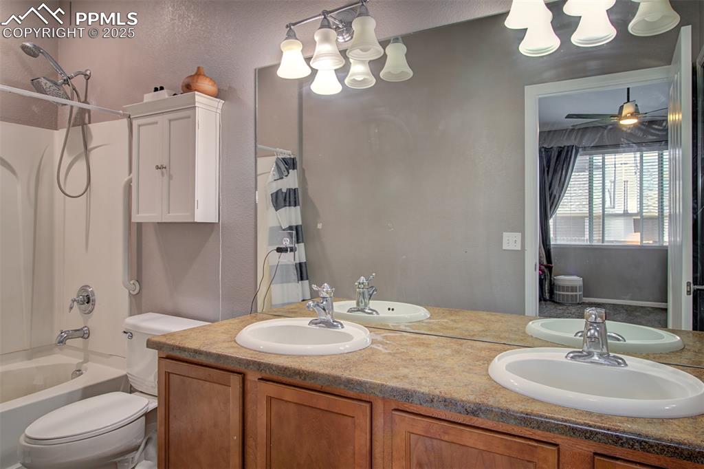 Image 5 of 21: Full bathroom with a chandelier, double vanity, and shower / bath combo wit
