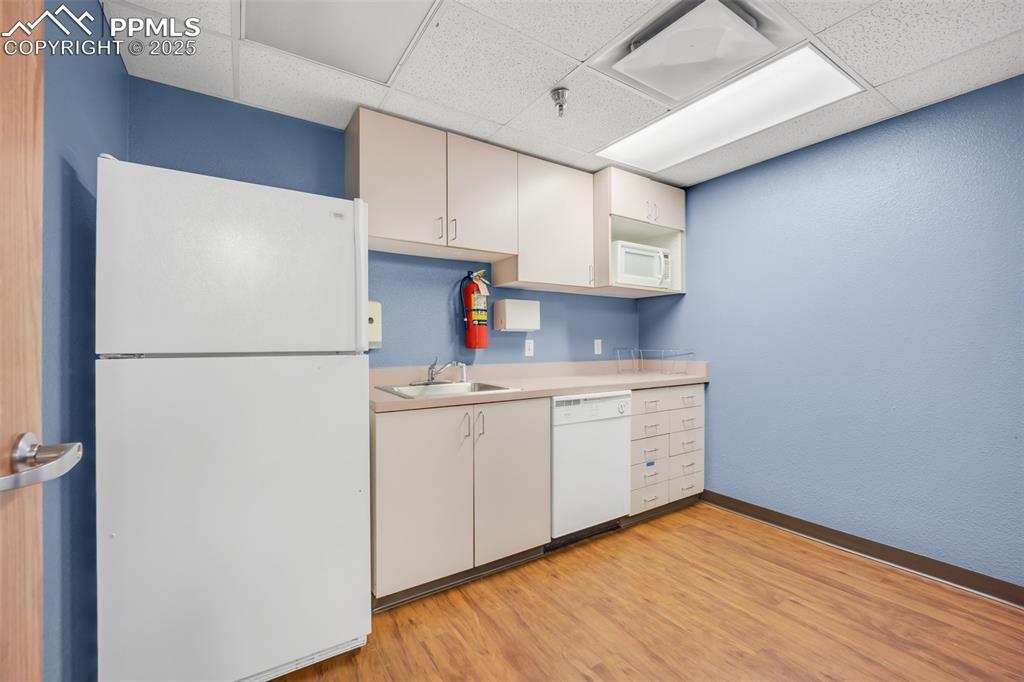 Image 19 of 49: Kitchen featuring white appliances, a paneled ceiling, light countertops, l