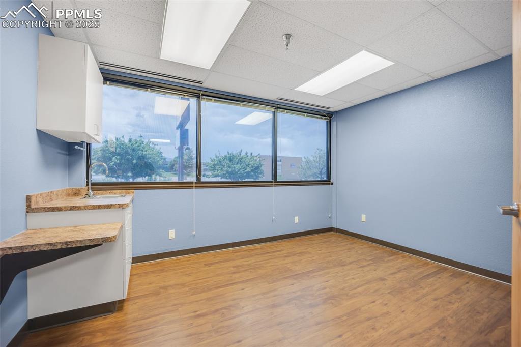 Image 23 of 49: Empty room featuring a paneled ceiling, light wood-type flooring, and fire