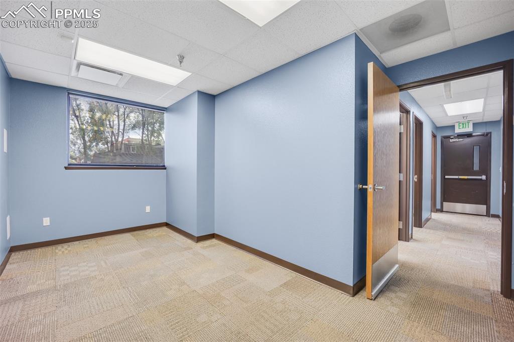 Image 30 of 49: Empty room with a paneled ceiling, carpet, and a pendent fire sprinkler