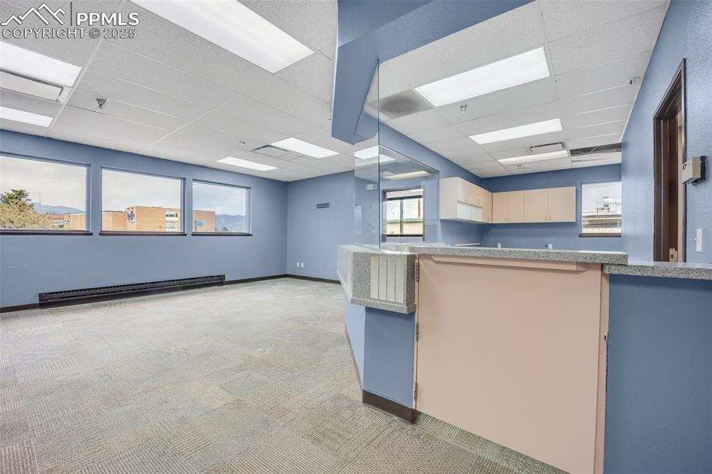 Image 35 of 49: Kitchen featuring a baseboard radiator, a paneled ceiling, and light colore