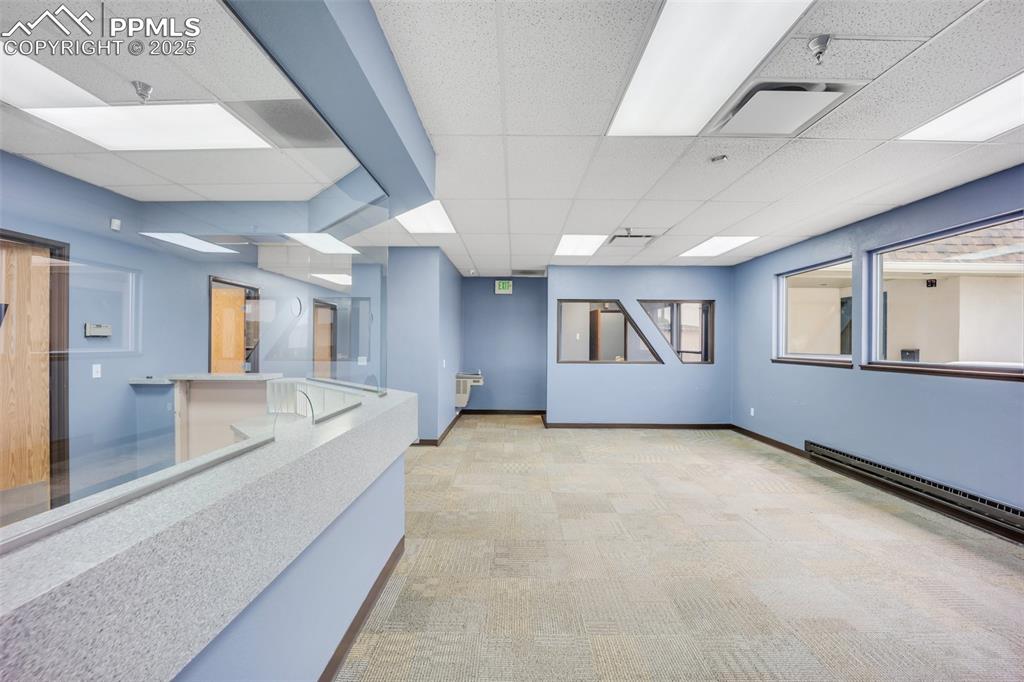 Image 36 of 49: Empty room with a paneled ceiling, light carpet, fire sprinkler in ceiling,