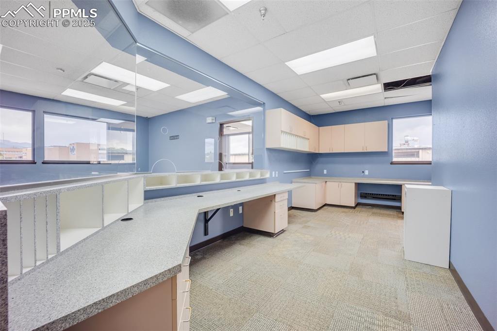 Image 39 of 49: Kitchen with a drop ceiling, light countertops, and light floors