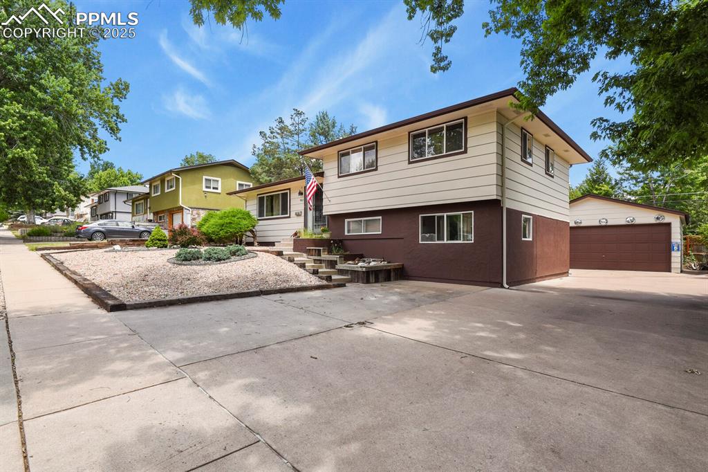 Image 2 of 30: Tri-level home with a garage and an outbuilding
