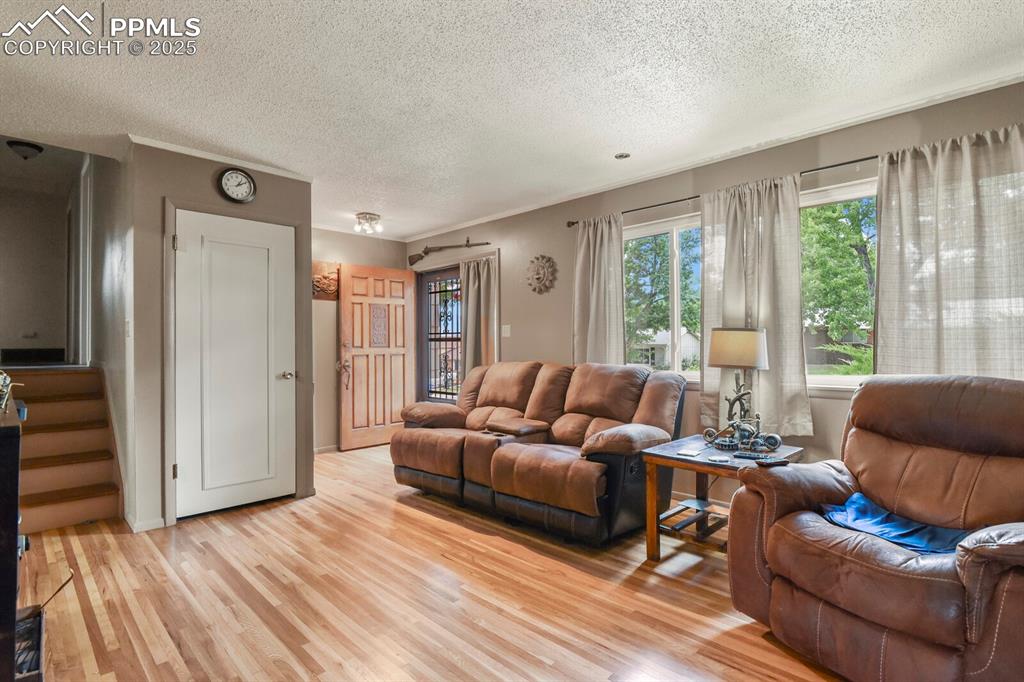 Image 4 of 30: Living area featuring light wood-style flooring, a textured ceiling, and st