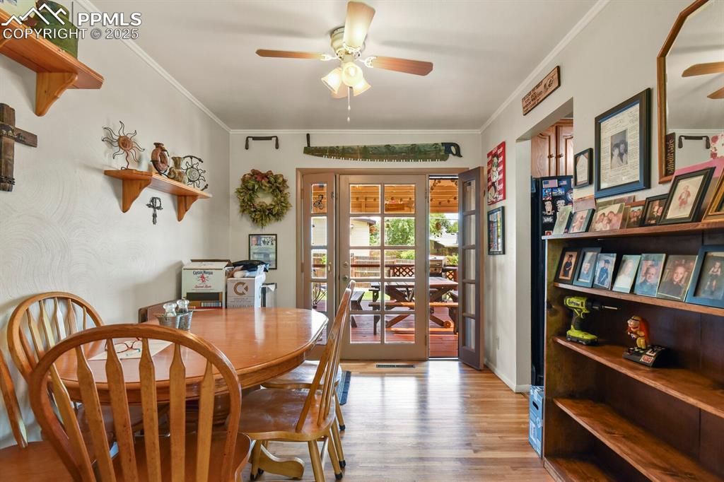 Image 7 of 30: Dining area with a ceiling fan, wood finished floors, and crown molding