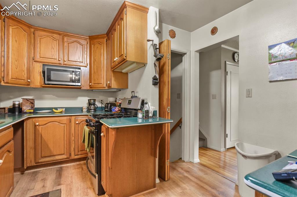 Image 9 of 30: Kitchen featuring appliances with stainless steel finishes, light wood-styl