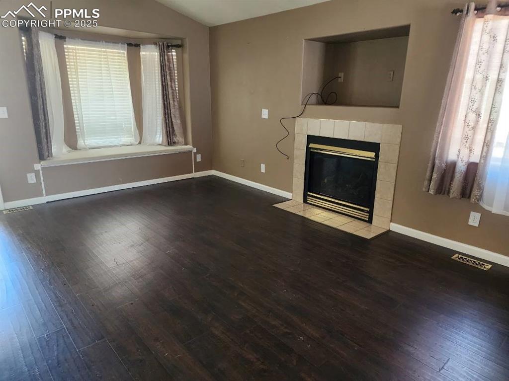 Image 10 of 17: Unfurnished living room featuring lofted ceiling, dark wood-style flooring,
